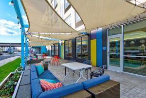 um pátio com sofás azuis, uma mesa e cadeiras em Tru By Hilton Ashburn One Loudoun, Va em Ashburn