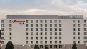 un grande edificio bianco con un cartello della farmacia di Hampton by Hilton Konstanz a Costanza