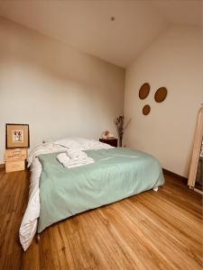 a bedroom with a bed with green sheets and a wooden floor at La Cour Verte Chambres d'Hôtes in Montépilloy