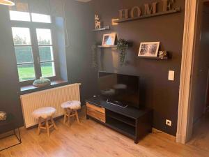 a living room with a flat screen tv and two stools at Appartement situé dans la nature des Hautes-Fagnes in Waimes