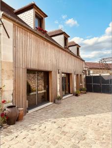 - un bâtiment avec des portes vitrées et une terrasse dans l'établissement La Cour Verte Chambres d'Hôtes, à Montépilloy