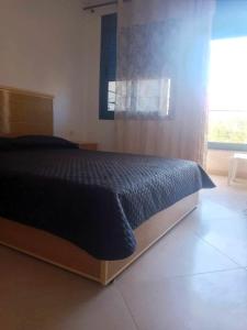 ein Schlafzimmer mit einem Bett und einem großen Fenster in der Unterkunft Family Beach Saïdia in Saidia 