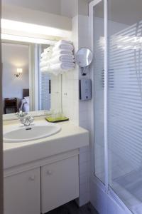 een witte badkamer met een wastafel en een douche bij Au Relais du Porhoet in Guilliers