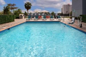 Home2 Suites By Hilton Miami Airport South Blue Lagoon في ميامي: مسبح كبير مع كراسي في مبنى