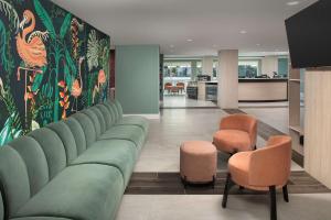 sala de estar con sofá verde y 2 sillas en Home2 Suites By Hilton Miami Airport South Blue Lagoon en Miami
