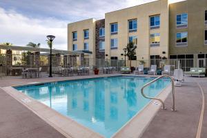 uma piscina num hotel com cadeiras e mesas em Hilton Garden Inn Temecula em Temecula