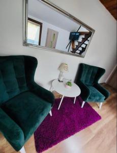 a living room with two chairs and a table and a mirror at JÓKAI Apartman in Komárno