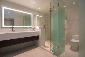 uma casa de banho com um lavatório e uma cabina de duche em vidro. em The Benson Portland, Curio Collection by Hilton em Portland
