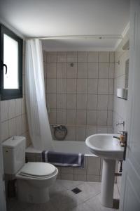 a bathroom with a toilet and a sink and a tub at Odysseas rooms in Kalón Nerón