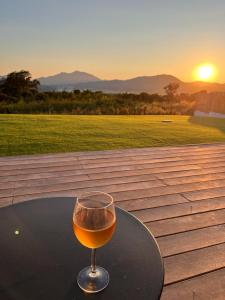una copa de vino sentada en una mesa con la puesta de sol en Splendide Villa avec Piscine, Sauna, Jacuzzi Villa Cookini près d'Ajaccio, en Bastelicaccia