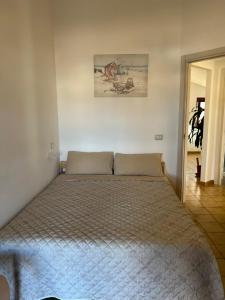 uma cama num quarto branco com uma colcha em Attico con Terrazza Vista Mare em Portoscuso