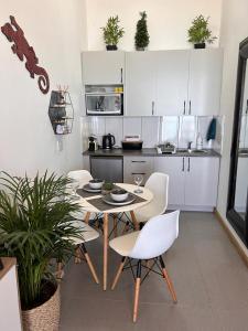 a kitchen with white cabinets and a table and chairs at Relax,Revive,Reset & enjoy the sounds of the sea! in Cape Town