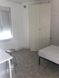 1 dormitorio con cama, taburete y ventana en Nice flat.Very near UCAM, UM university.Murcia, en Espinardo