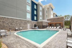 una piscina con sillas y un edificio en Homewood Suites By Hilton Mcdonough en McDonough
