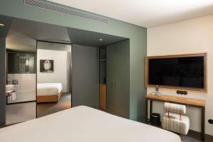 a bedroom with a bed and a flat screen tv at Se Catedral Hotel Porto, Tapestry Collection By Hilton in Porto
