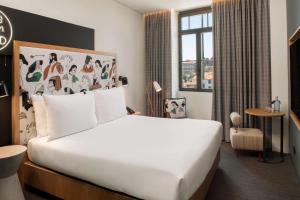 a hotel room with a large white bed and a window at Se Catedral Hotel Porto, Tapestry Collection By Hilton in Porto