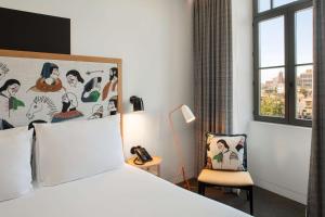 a bedroom with a bed and a chair and a window at Se Catedral Hotel Porto, Tapestry Collection By Hilton in Porto