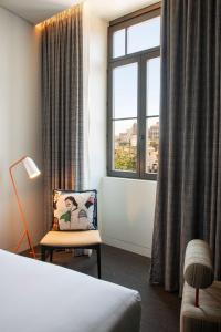 a hotel room with a bed and a chair and a window at Se Catedral Hotel Porto, Tapestry Collection By Hilton in Porto