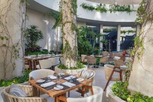 a restaurant with tables and chairs and trees at Hilton Garden Inn Cancun Airport in Cancún