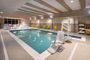 a pool in a hotel room with yellow chairs at Home2 Suites By Hilton Richmond Short Pump in Richmond