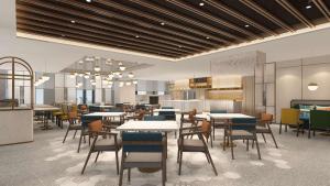 a restaurant with tables and chairs and a kitchen at Hilton Garden Inn Jinzhou Central Street in Jinzhou
