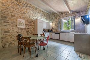 une cuisine avec une table et des chaises ainsi qu'un mur en pierre dans l'établissement Mazet Pierre de Vers - Le Mas des Olivers Nîmes, à Nîmes