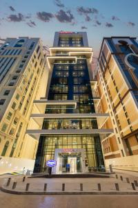 Hampton By Hilton Doha Old Town في الدوحة: مبنى طويل مع علامة أمامه