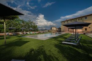 a pool with chairs and umbrellas in a yard at San Lorenzo Apartments in Colle Val D'Elsa