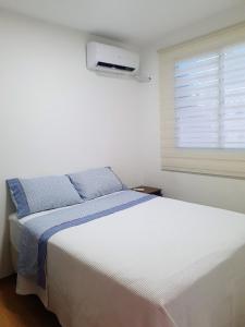 a bedroom with a white bed and a window at Apto NOVO região Shopping Pantanal/Centro Político in Cuiabá