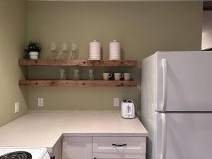 a kitchen with a white refrigerator and shelves with dishes at CAIA Lakeside Retreat - Sunken Lake in New Minas