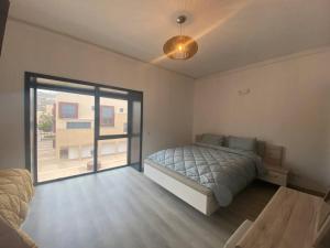 ein Schlafzimmer mit einem Bett und einem großen Fenster in der Unterkunft New Luxury Duplex Apt Taghazout in Taghazout