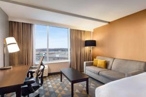 潘特克莱尔Doubletree By Hilton Pointe Claire Montreal Airport West的酒店客房配有一张床、一张沙发和一张书桌。