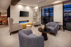 a living room with chairs and a tv on a wall at Hilton Garden Inn Haymarket in Haymarket