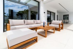 Una sala de estar con muebles blancos y grandes ventanales. en ALBA SEA VILLA, en Chiclana de la Frontera