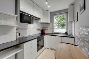 cocina con armarios blancos y encimera de madera en Comfort Apartments Żywiecka en Gdansk