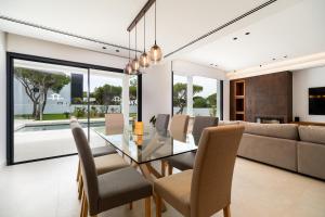 Un comedor con una mesa de cristal y sillas. en ALBA SEA VILLA, en Chiclana de la Frontera
