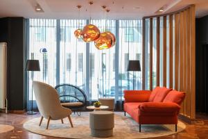 a living room with an orange couch and chairs at DoubleTree by Hilton Hannover Schweizerhof in Hannover