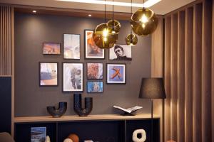 a living room with a wall with pictures and a lamp at DoubleTree by Hilton Hannover Schweizerhof in Hannover