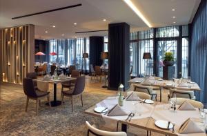 ハノーファーにあるDoubleTree by Hilton Hannover Schweizerhofのテーブルと椅子、窓のあるレストラン