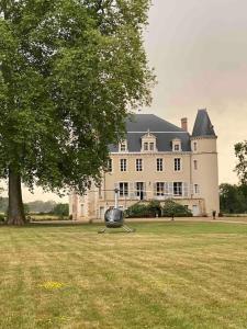 ein großes Haus mit einem großen Baum davor in der Unterkunft Belle dépendance du château : LE LOGIS in Ardentes