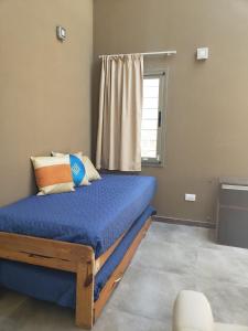 1 dormitorio con cama con sábanas azules y ventana en Casa Serrana en Córdoba