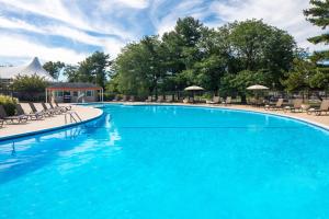 a large blue swimming pool with chairs and umbrellas at DoubleTree by Hilton Cherry Hill Philadelphia in Cherry Hill