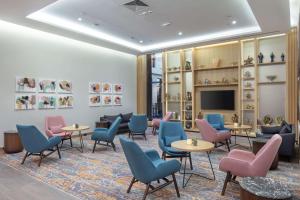 una sala de espera con mesas, sillas y TV en Hilton Garden Inn Erzurum, en Erzurum
