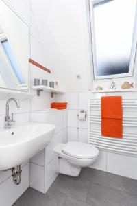 ein weißes Bad mit einem Waschbecken und einem WC in der Unterkunft Ferienhaus Daniela in Neuharlingersiel