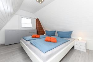 Schlafzimmer mit einem Bett mit blauen und orangefarbenen Kissen in der Unterkunft Ferienhaus Daniela in Neuharlingersiel