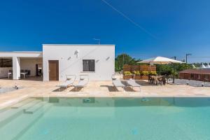 Una piscina con sillas y una mesa y una casa. en Valle d'Itria IN, en Martina Franca