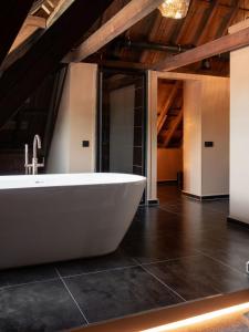 d'une grande salle de bains pourvue d'une baignoire blanche. dans l'établissement B&B Slapen bij DKW, à Oldebroek