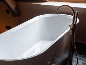 a white bath tub in a bathroom next to a window at B&B Slapen bij DKW in Oldebroek