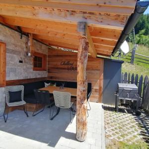 a patio with a table and chairs under a wooden roof at Almchalet Wieslhütte in Gerlosberg