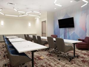 Sala de conferencias con mesas y sillas y TV de pantalla plana en Hilton Garden Inn Jeffersonville, In, en Jeffersonville